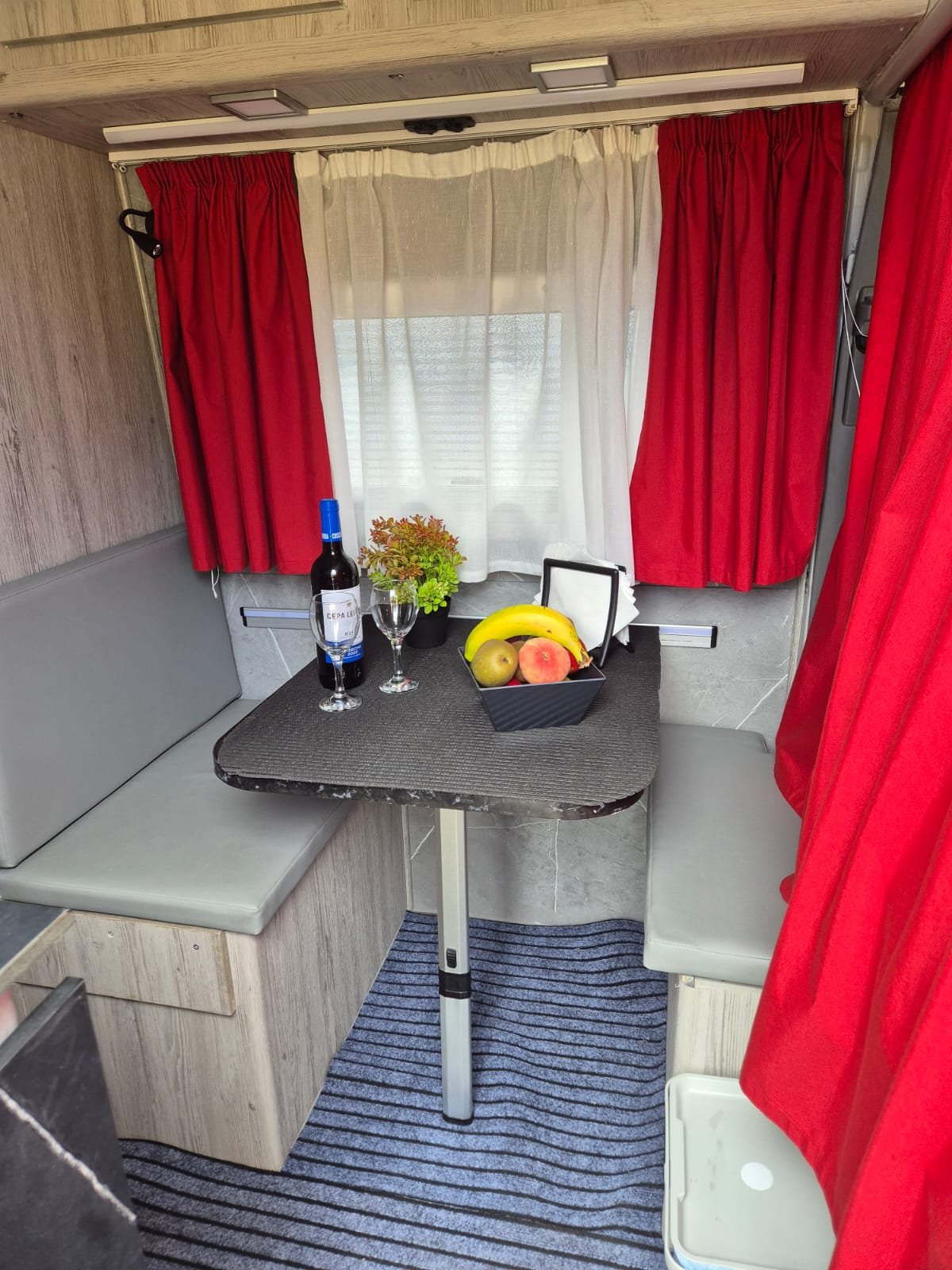 Salón comedor de la camper Mercedes Sprinter con cortinas y mesa